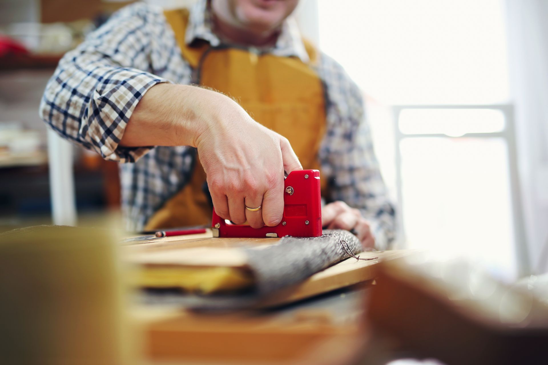 A man is using a stapler on a piece of wood.