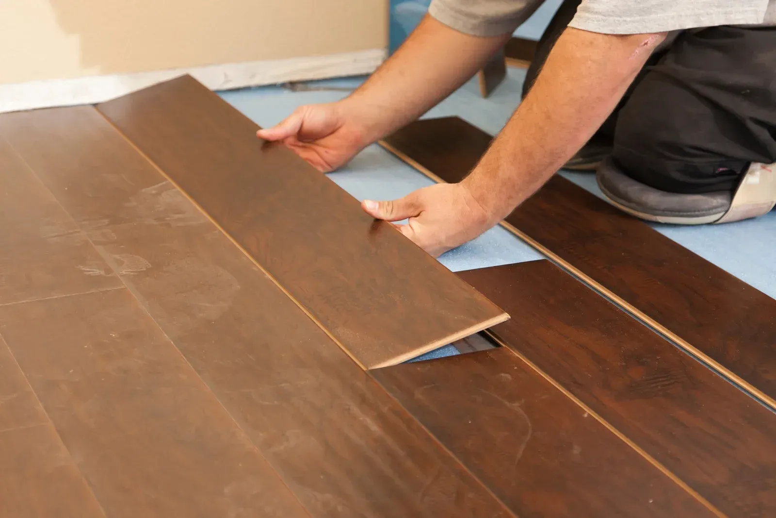 A man is laying a piece of wood on the floor