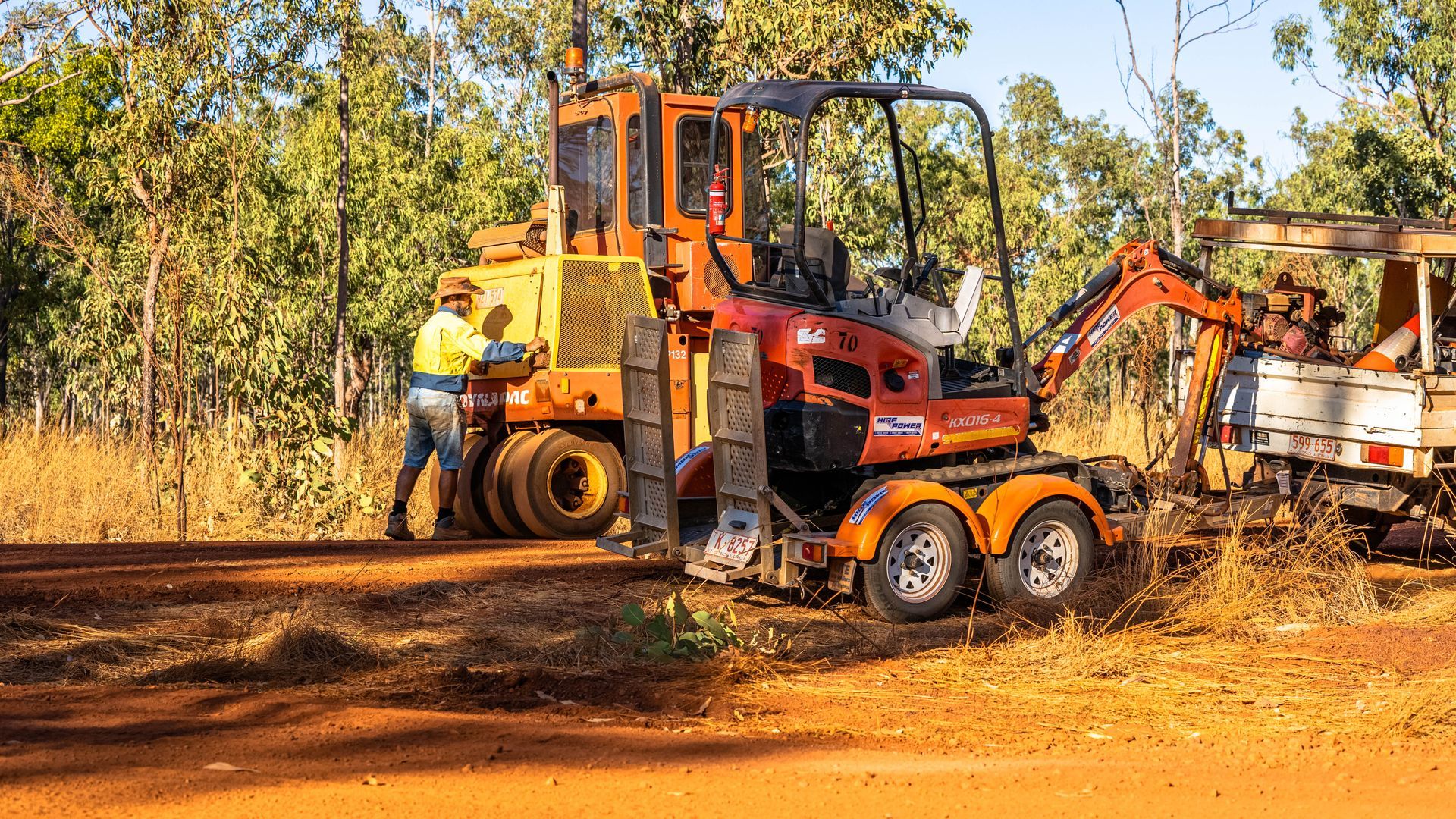 A man is standing next to a bulldozer on a dirt road.