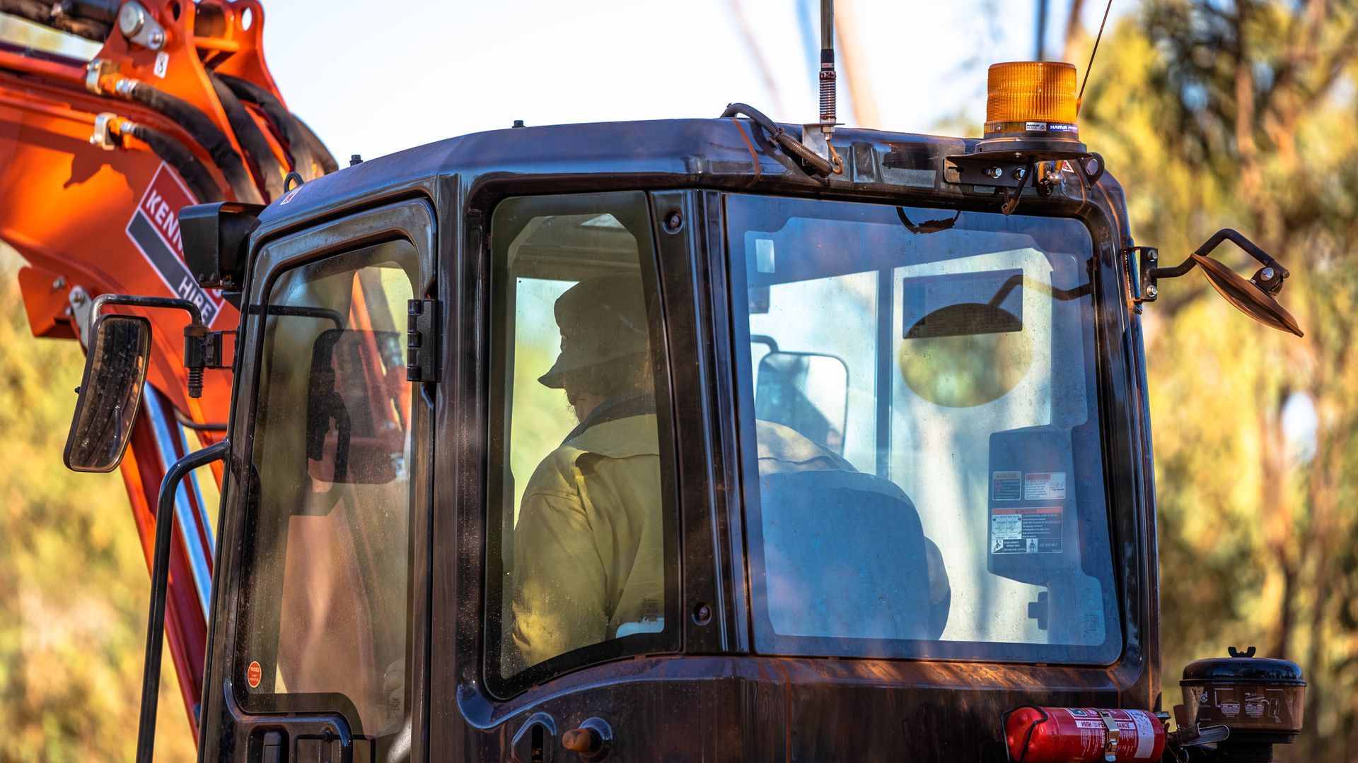 A man is driving an excavator on a road.