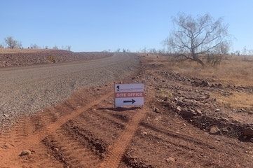 A sign is sitting on the side of a dirt road.