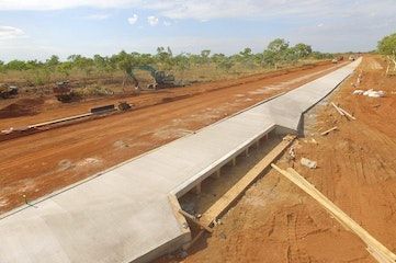 An aerial view of a road under construction in the middle of a dirt field.