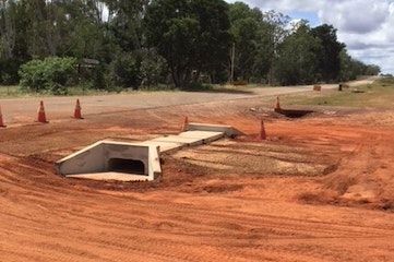 A dirt road with a concrete drain in the middle of it.