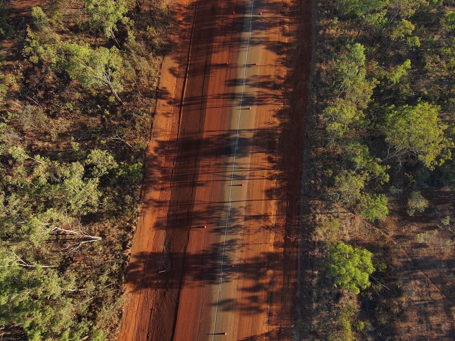 An aerial view of a dirt road surrounded by trees