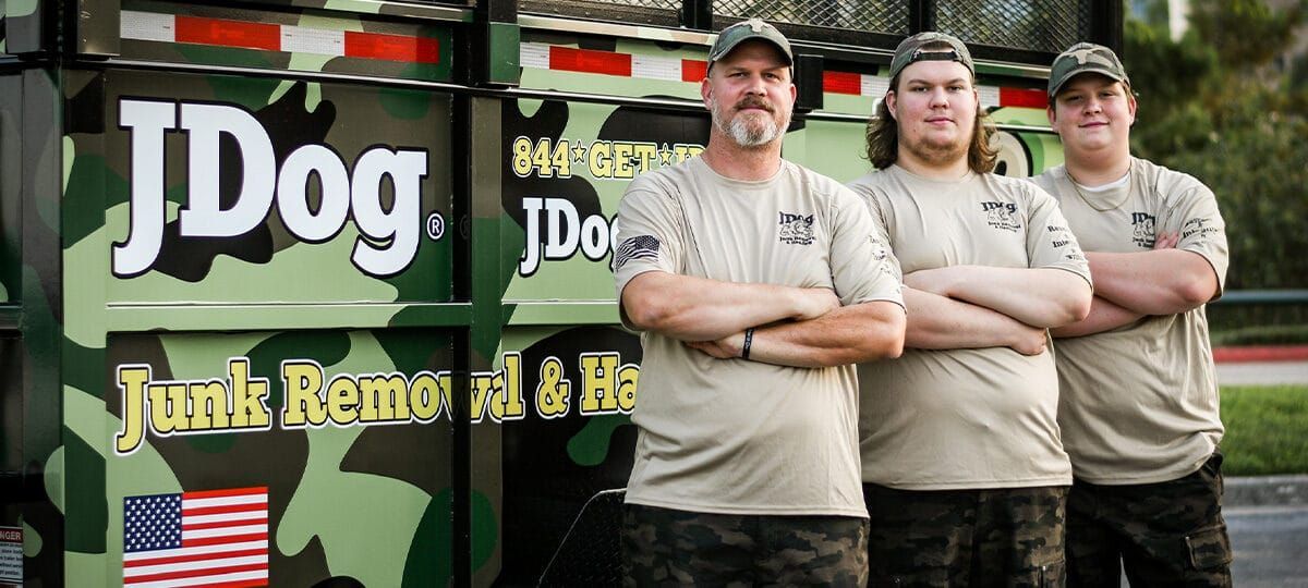 JDog Junk Removal truck with camouflage design, parked on a driveway.