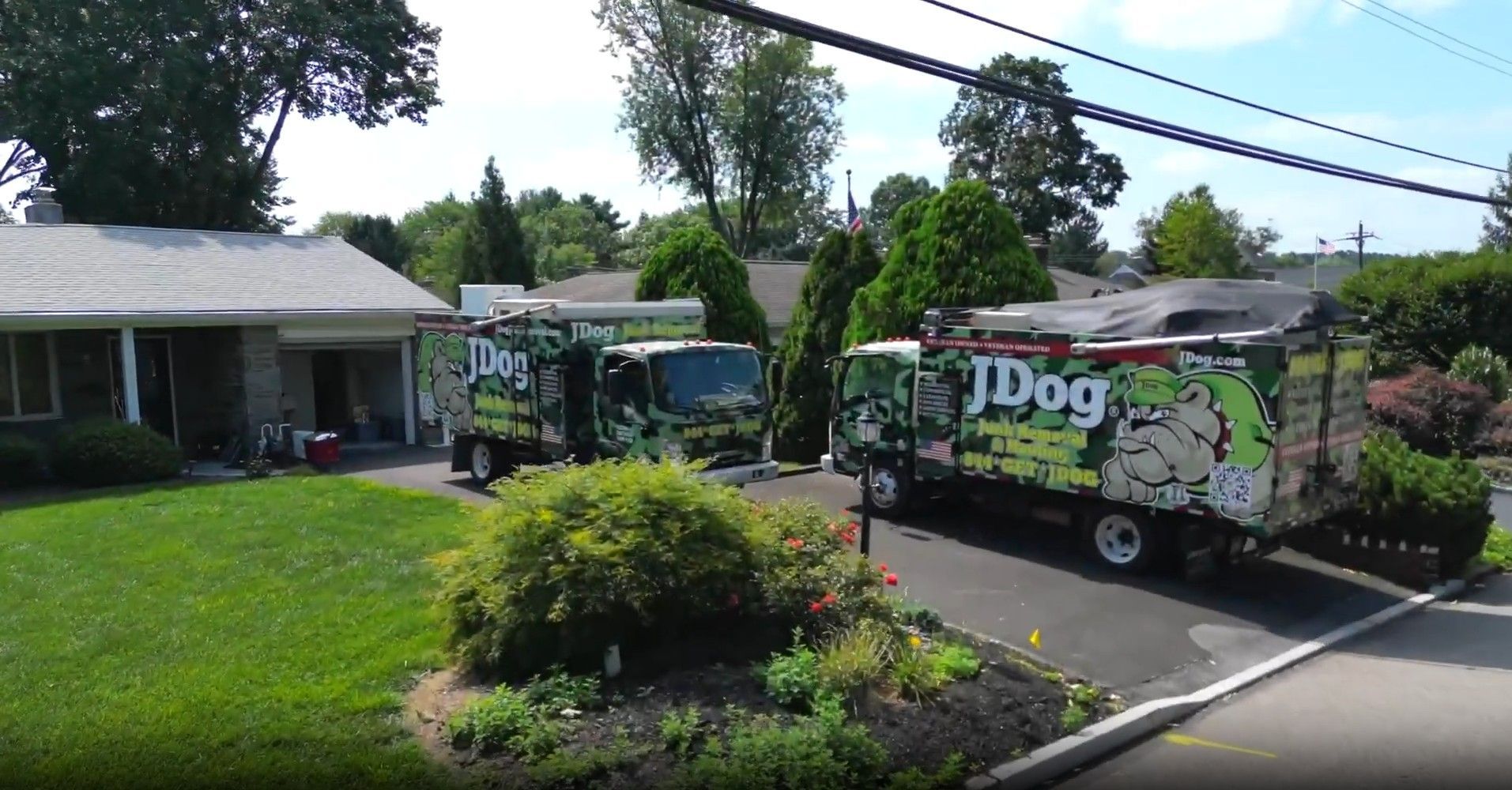 Two JDog trucks parked in front of a house, possibly for landscaping or removal services.
