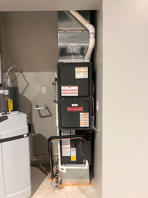 Furnace and air handler unit in a closet. Ductwork and water softener visible.