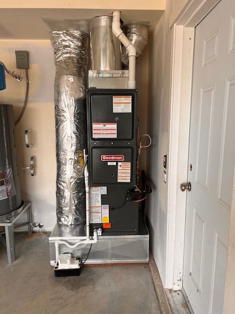 Furnace unit with ductwork and a white door in a garage.