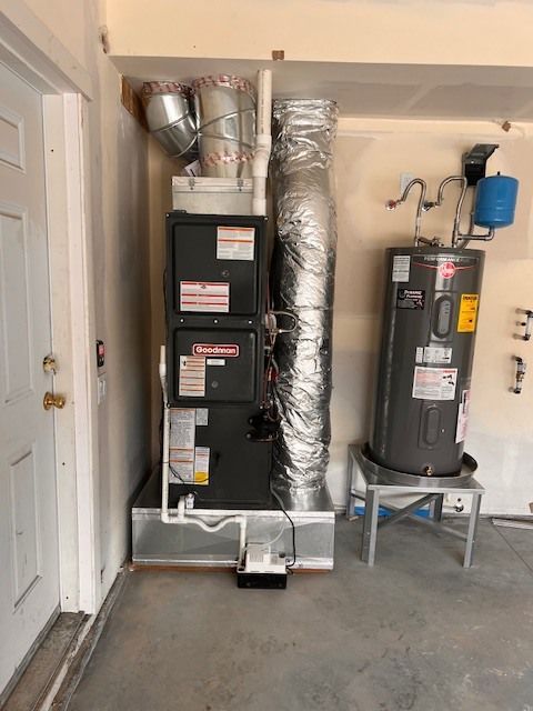 Furnace and water heater in a garage next to a white door.