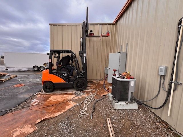 Forklift near building, lifting equipment. An outdoor setting with an overcast sky.