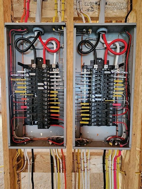 Two electrical panels with various colored wires inside. Black, red, white, yellow wires are visible.