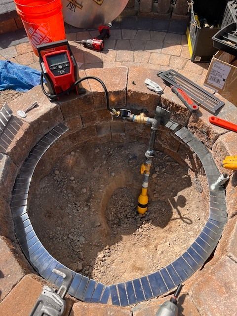 Fire pit under construction with gas line and tools.