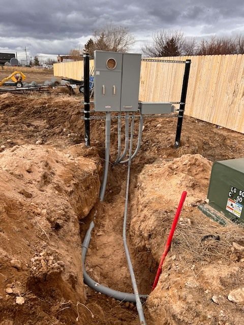 Electrical meter box with conduit running in a trench in an unfinished construction site.