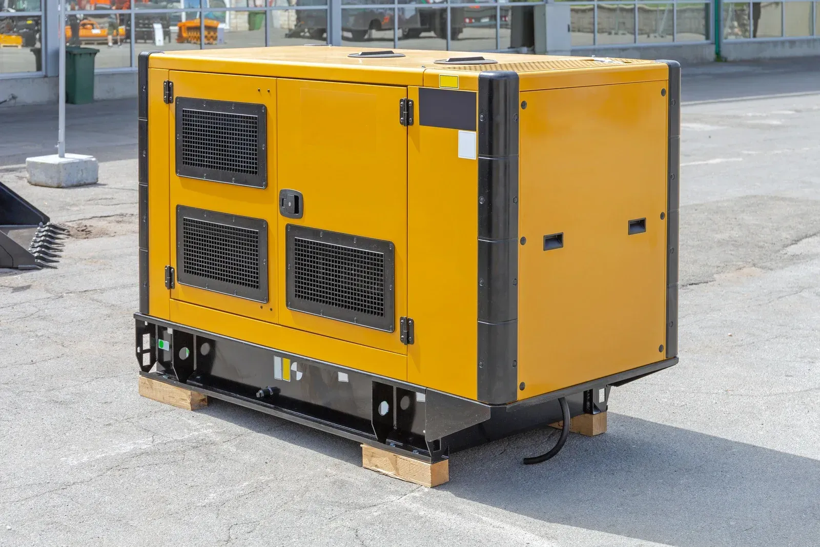 Yellow and black industrial generator on a pallet outdoors.