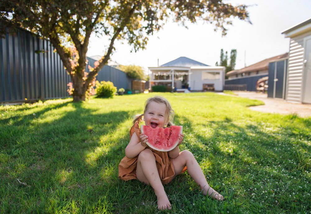Girl Eating Watermelon — Sydney, NSW — Emerald Lawn Landscape