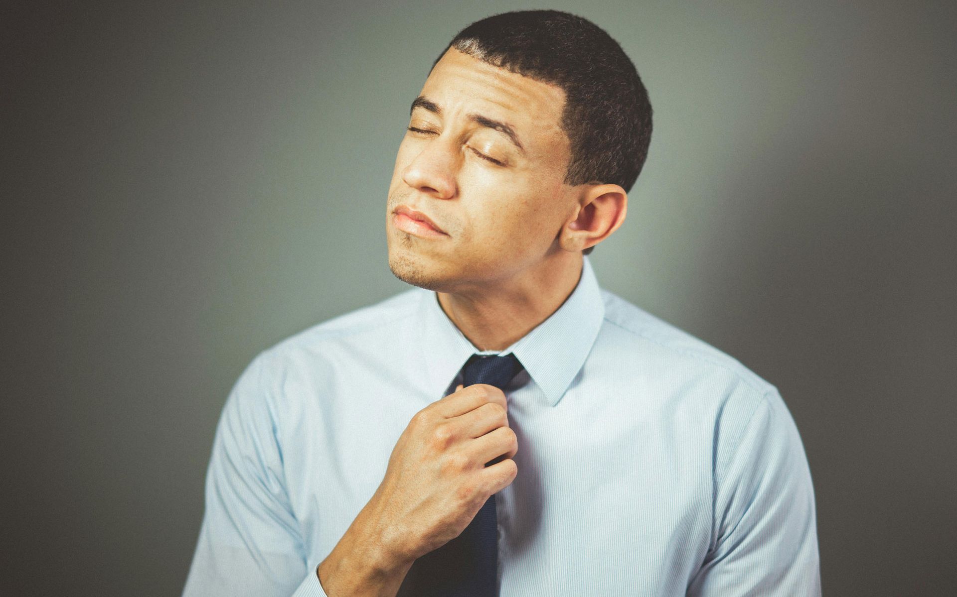 A man in a white shirt and tie is anxiously adjusting his tie.