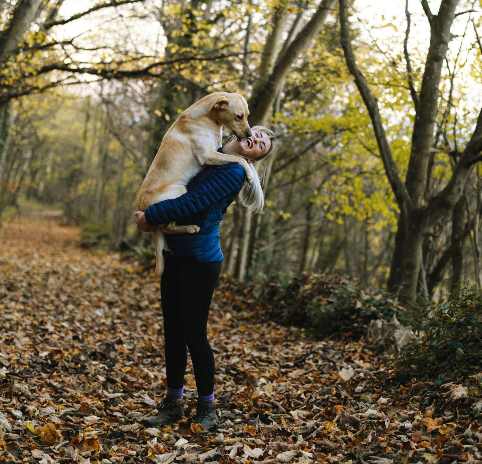 A woman is holding a dog in her arms in the woods