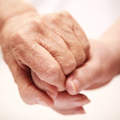 Zwei Hände halten sich gegenseitig. Eine Hand einer älteren und eine Hand einer jüngeren Person.