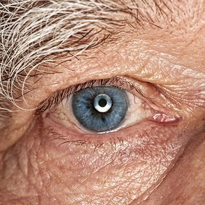 Nahaufnahme eines blauen Auges mit erkennbar grauen Augenbrauen. Blick direkt in die Kamera.