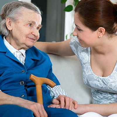Pflege- und Betreuungskraft im Gespräch mit einer älteren Dame.