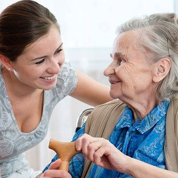 Pflege- und Betreuungskraft im Gespräch mit einer älteren Dame
