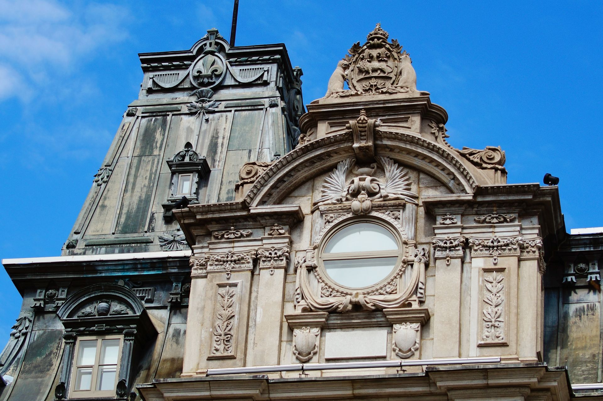 Façade de bâtiment ornée avec des sculptures élaborées et une horloge contre un ciel bleu.