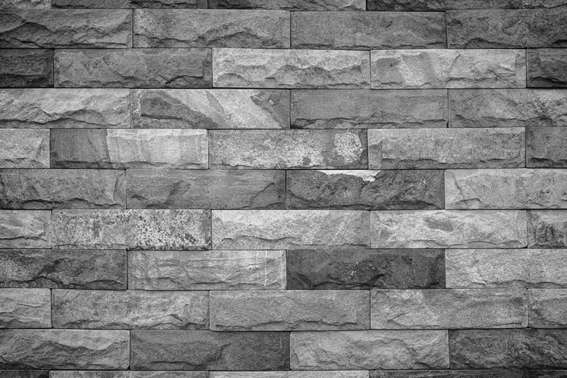 Mur de briques noires et blanches avec différentes nuances de gris et une surface texturée.