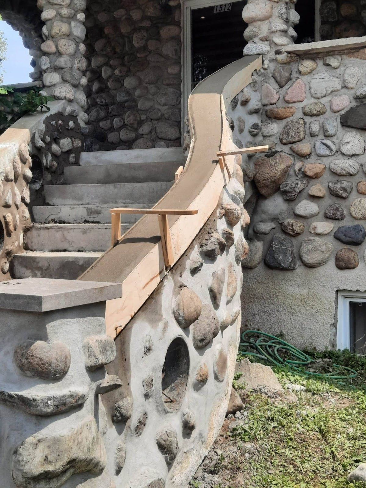 Entrée du bâtiment en pierre avec escalier et rampe de fortune pour l'accessibilité.