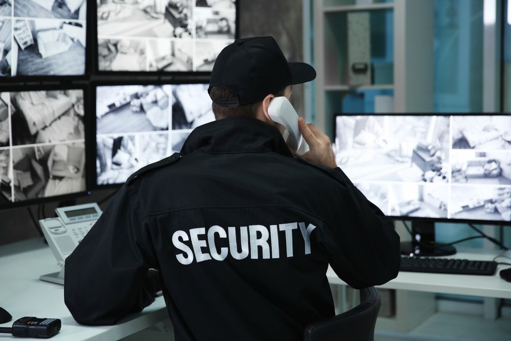 A Security Guard on Phone, Watching Surveillance Screens at a Desk — Clinton Security Services In Tamworth, NSW