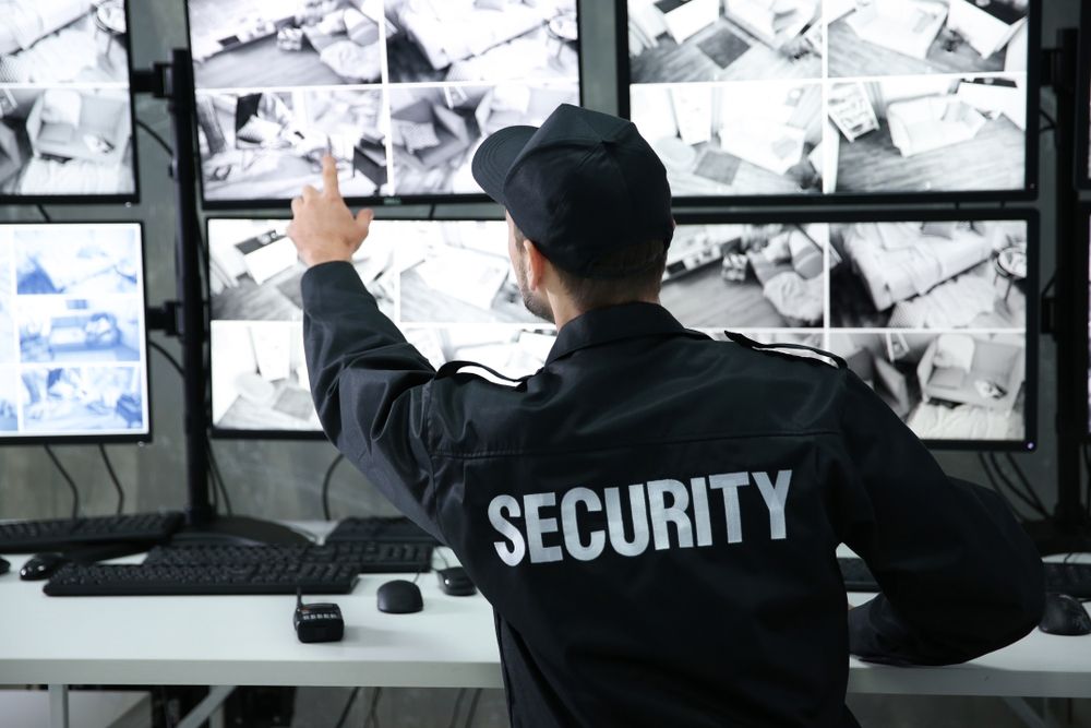 A Security Guard Pointing at a Monitor Wall, Monitoring Surveillance Footage — Clinton Security Services In Moree, NSW