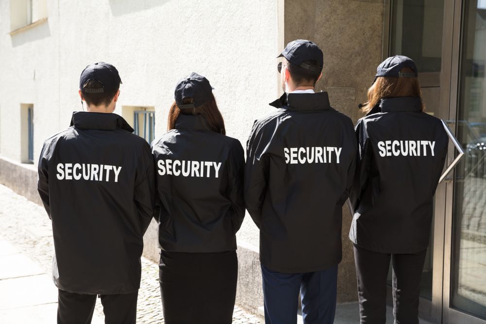 A Four Security Guards in Black Jackets and Caps — Clinton Security Services In Goondiwindi, QLD