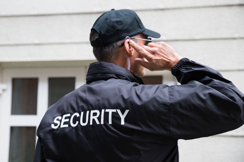 A Security Guard in Black Uniform With Earpiece, Standing Outside a Building — Clinton Security Services In Warwick, QLD