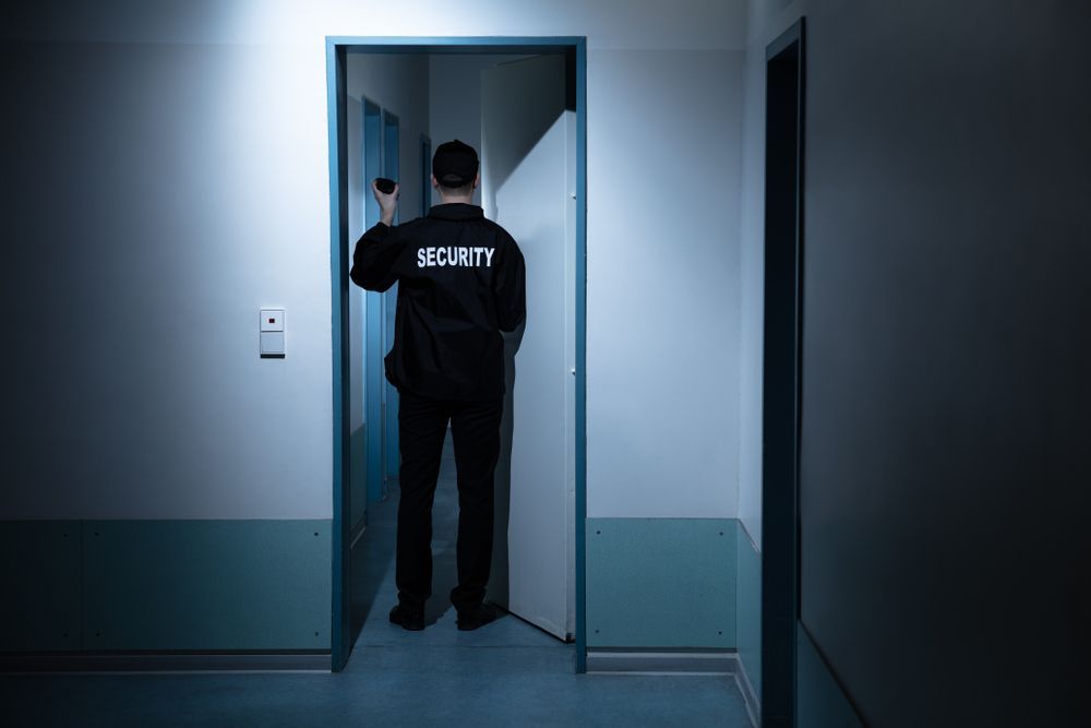 Security Guard With Flashlight, Checking a Hallway — Clinton Security Services In Armidale, NSW