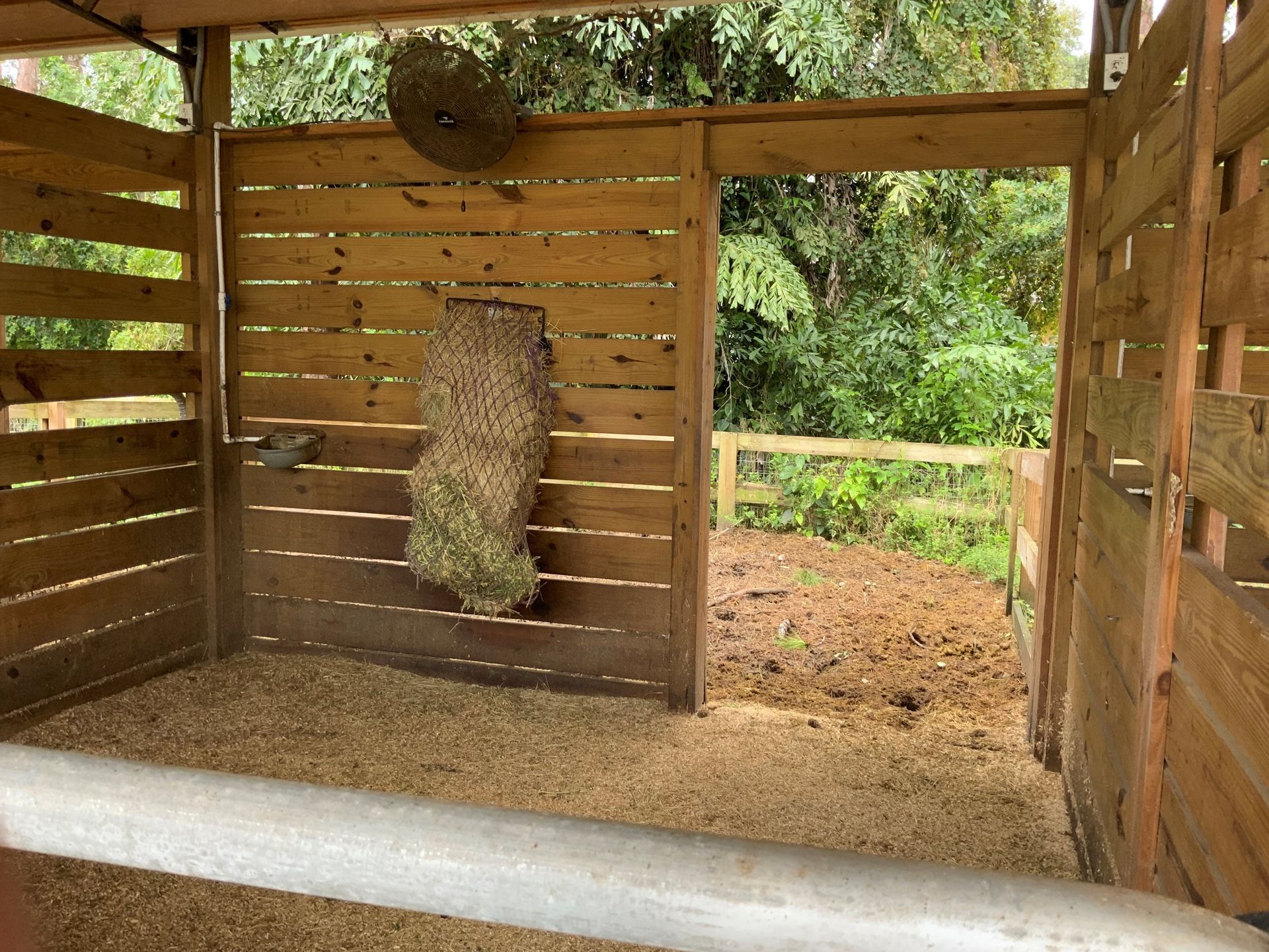 A wooden shed with a hay bale hanging on the wall