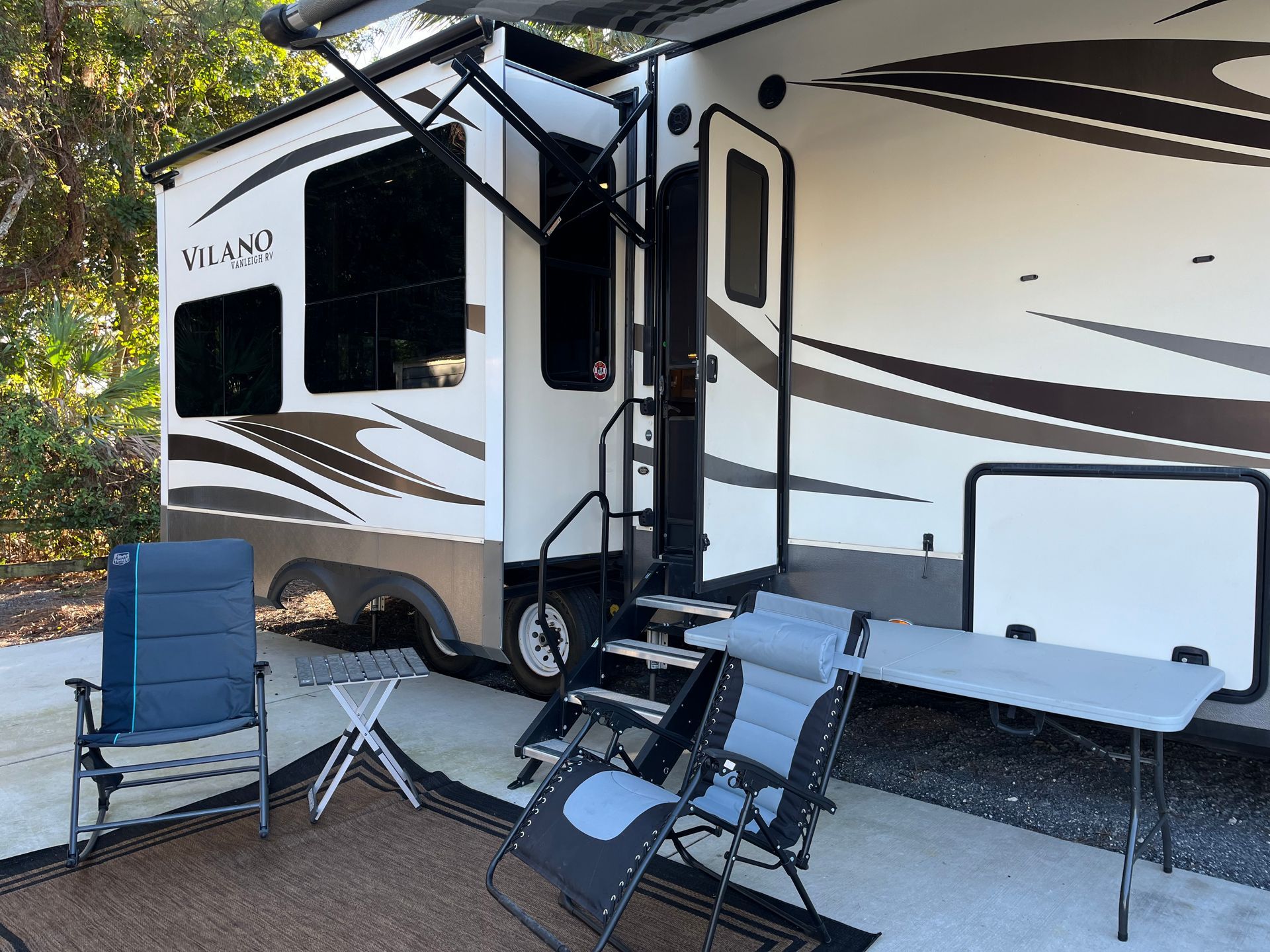 A Rv Is Parked Next to A Table and Chairs.