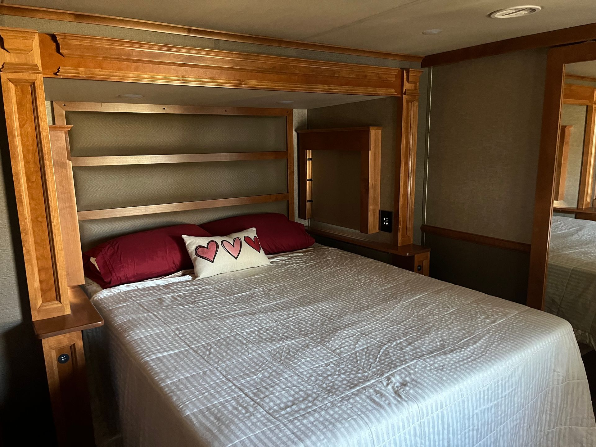 A bed with a wooden headboard and pillows in a bedroom.