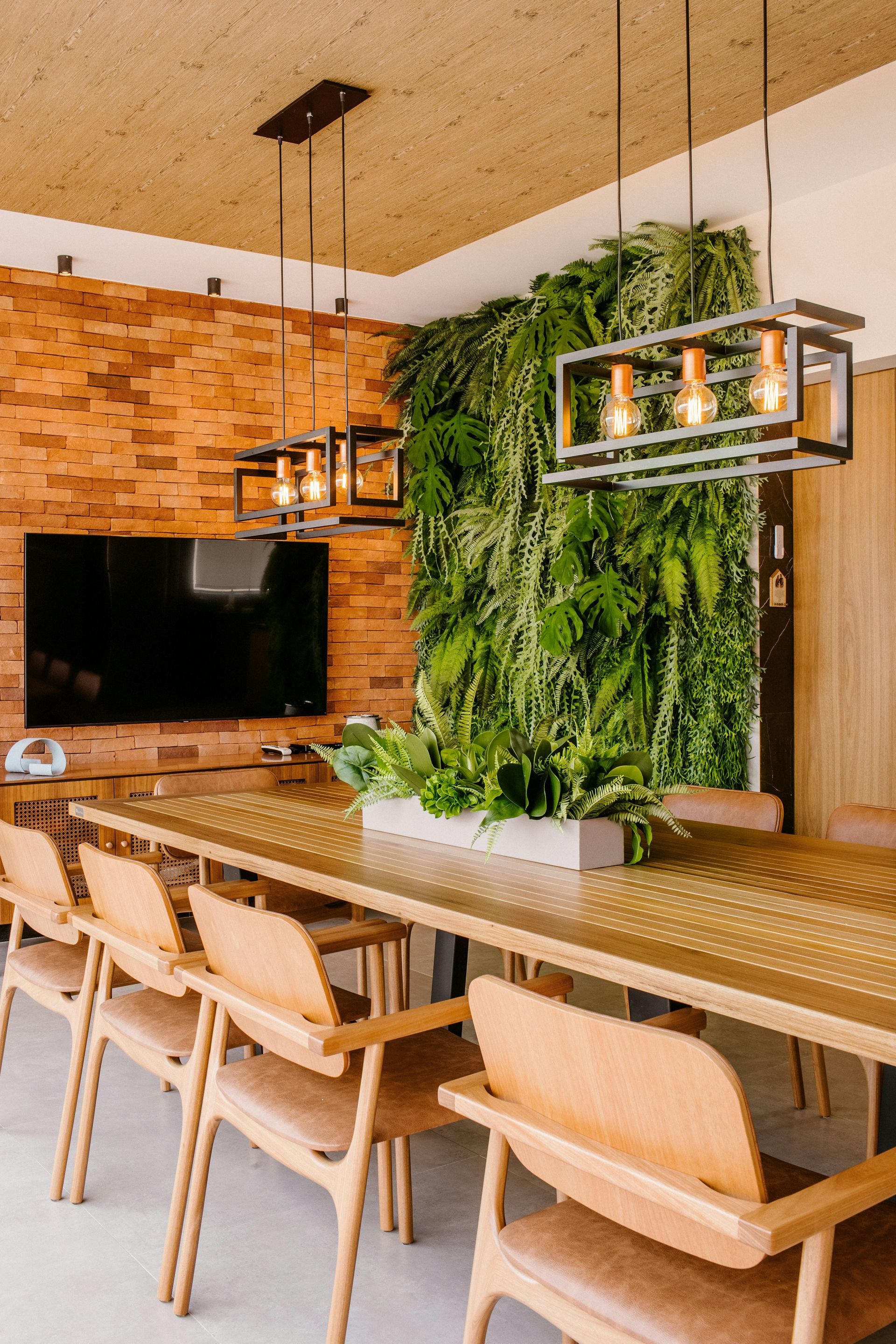 A dining room with a table and chairs and a wall of plants.