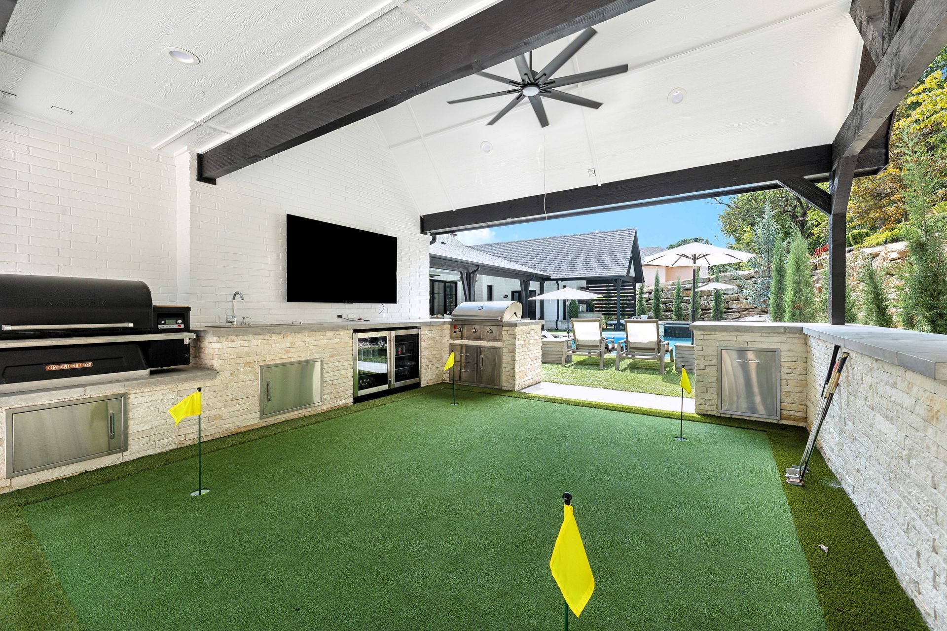 Covered outdoor entertainment space with a putting green, grill, and TV.
