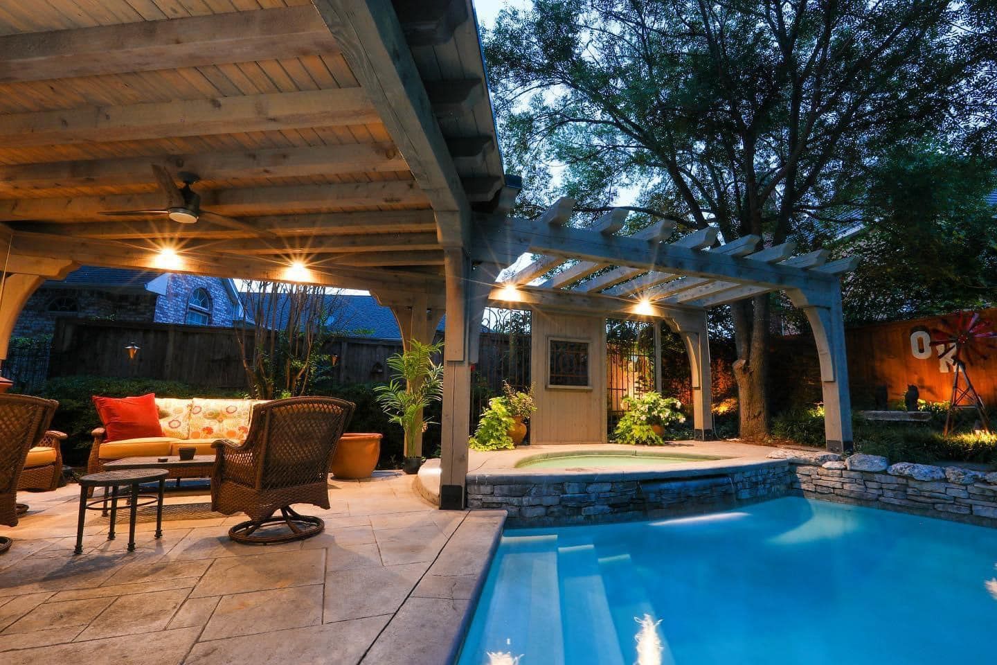 Outdoor patio with a pool and spa.  Relaxing area with a covered seating, and ambient lighting at night.