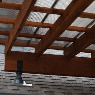 Wooden pergola with corrugated plastic roof panels, mounted on a roof with a dark metal support.