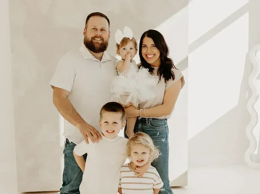 Family of five smiles at the camera in a white studio.