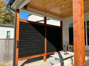 Outdoor patio with black privacy screen and wood accents.