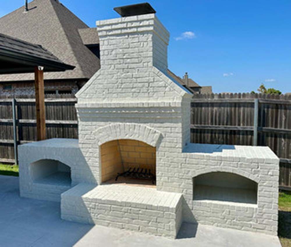 Outdoor brick fireplace with white painted finish, integrated oven and storage.