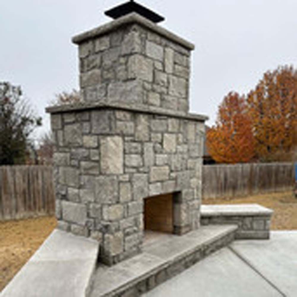Stone outdoor fireplace with a concrete base.