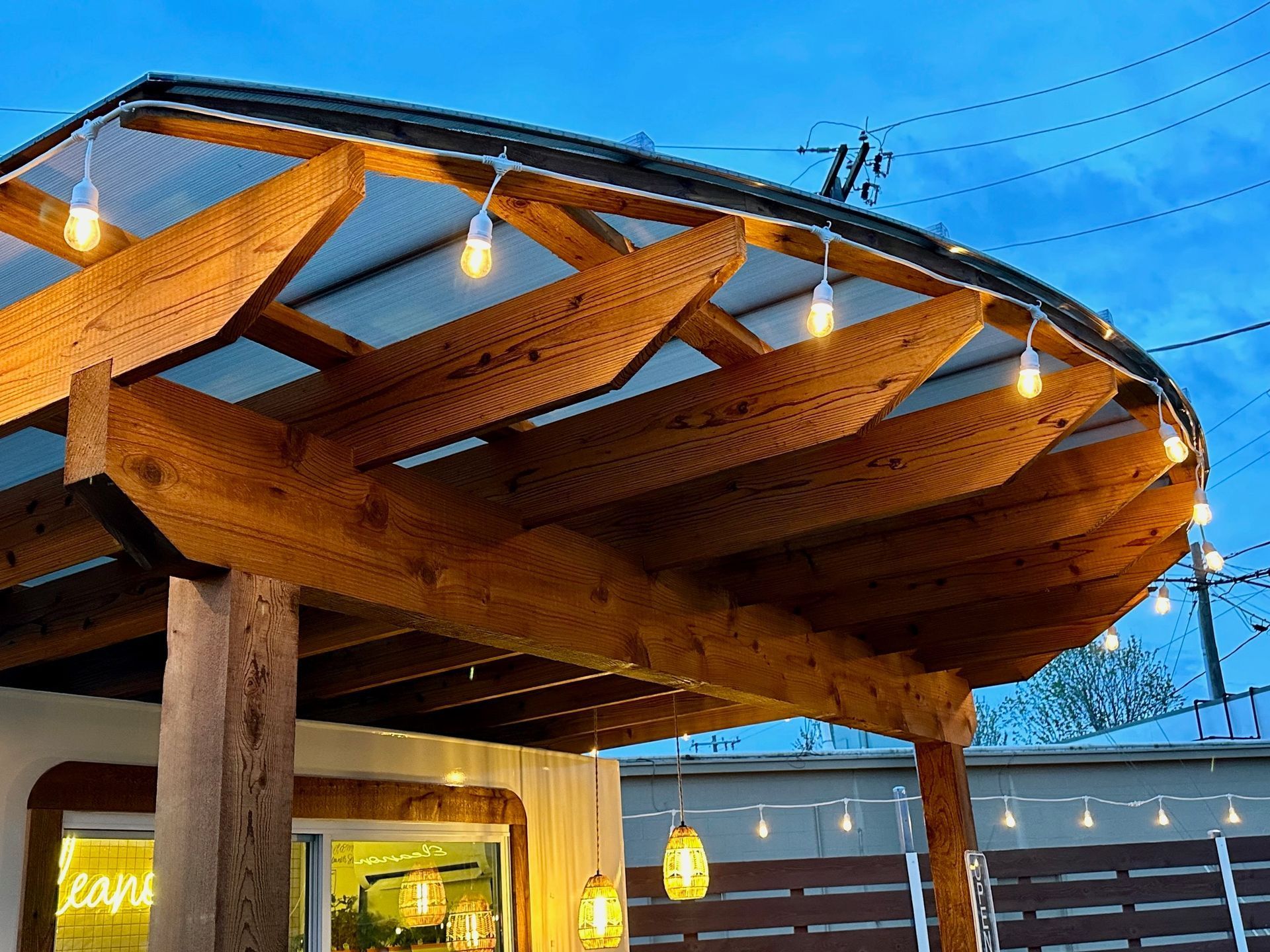 Wooden pergola with string lights; blue sky backdrop.