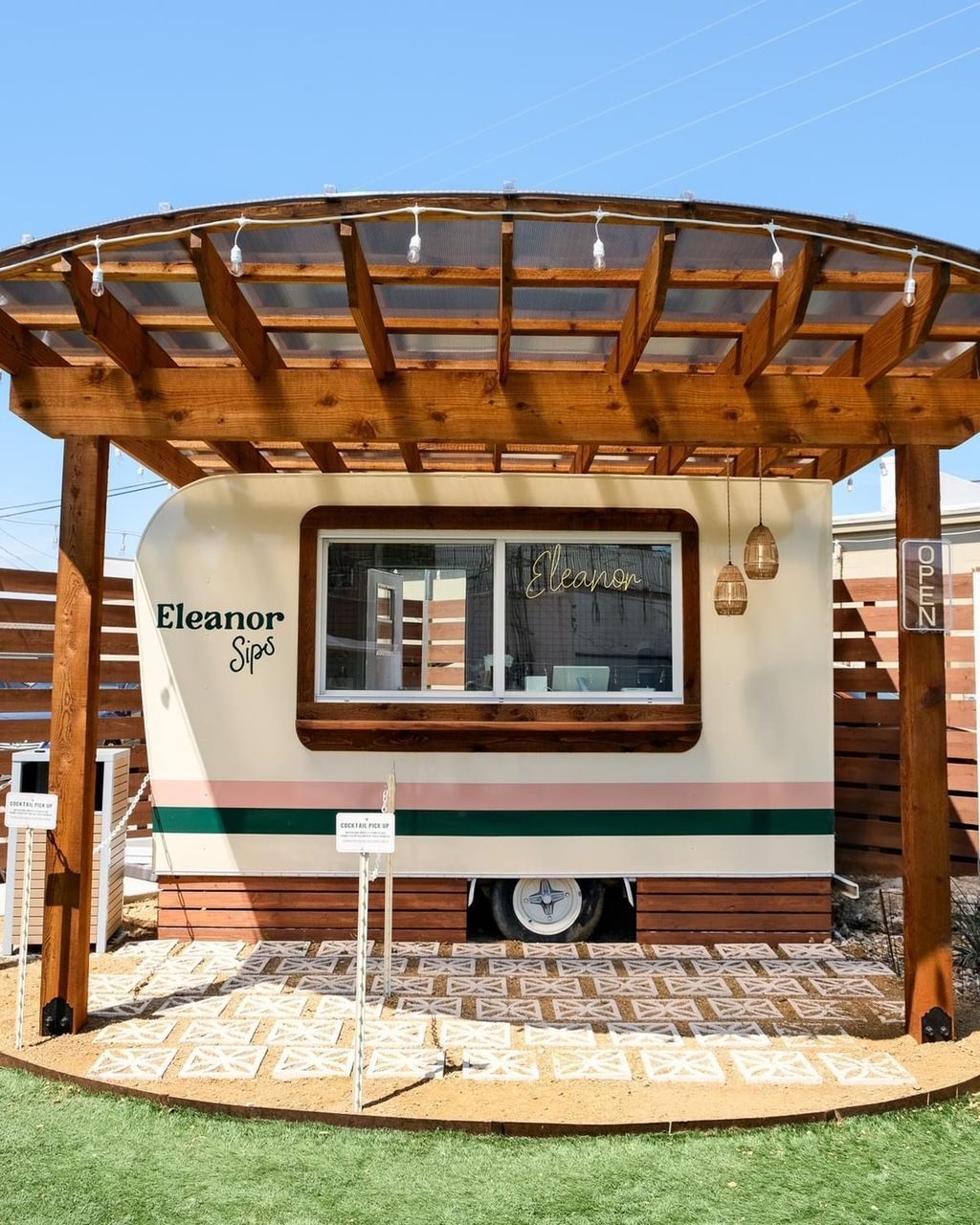 A vintage campervan spa under a wooden pergola, with pink and green accents.