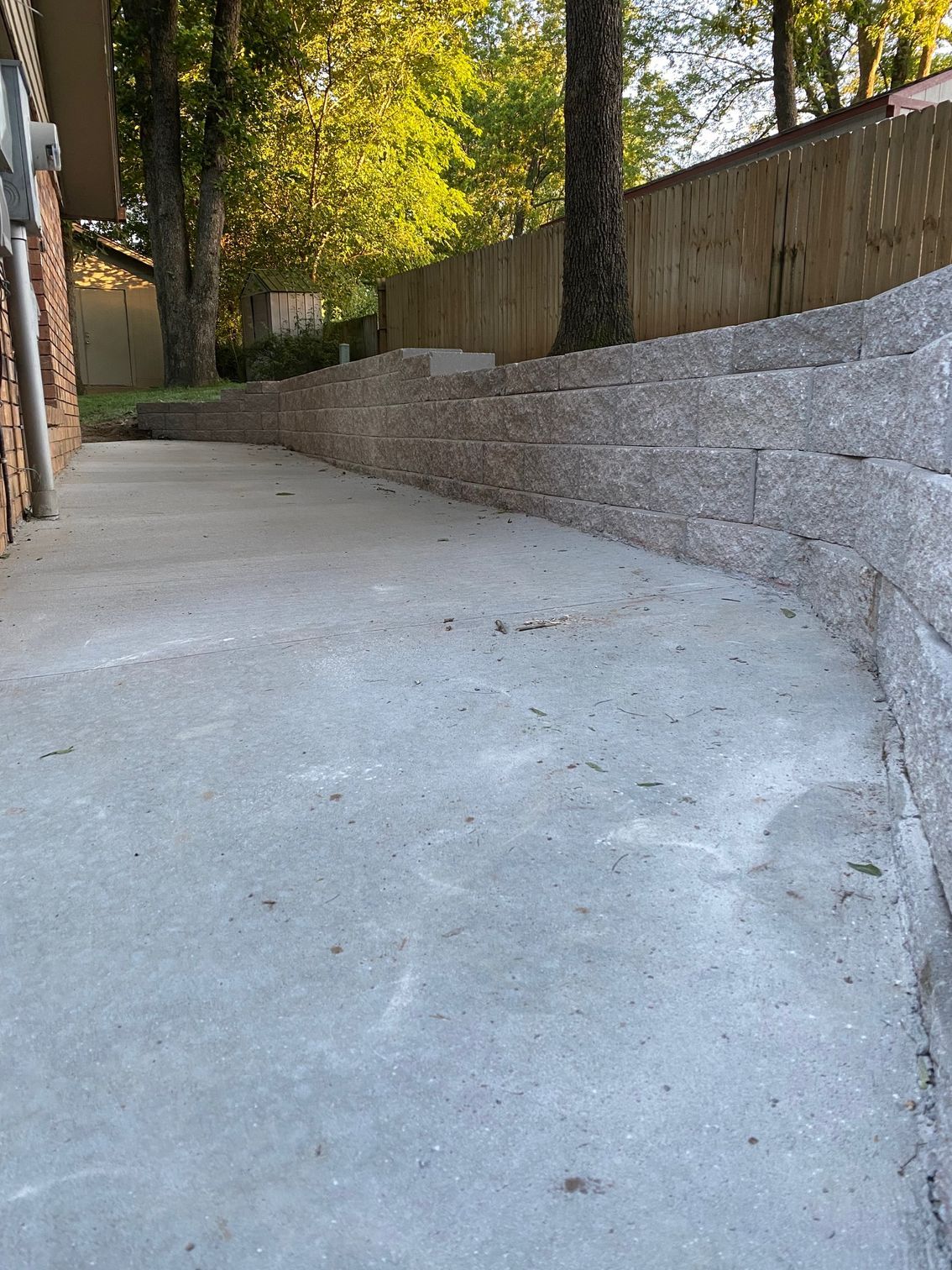 Brick patterned, dark gray concrete walkway curving through a green lawn.