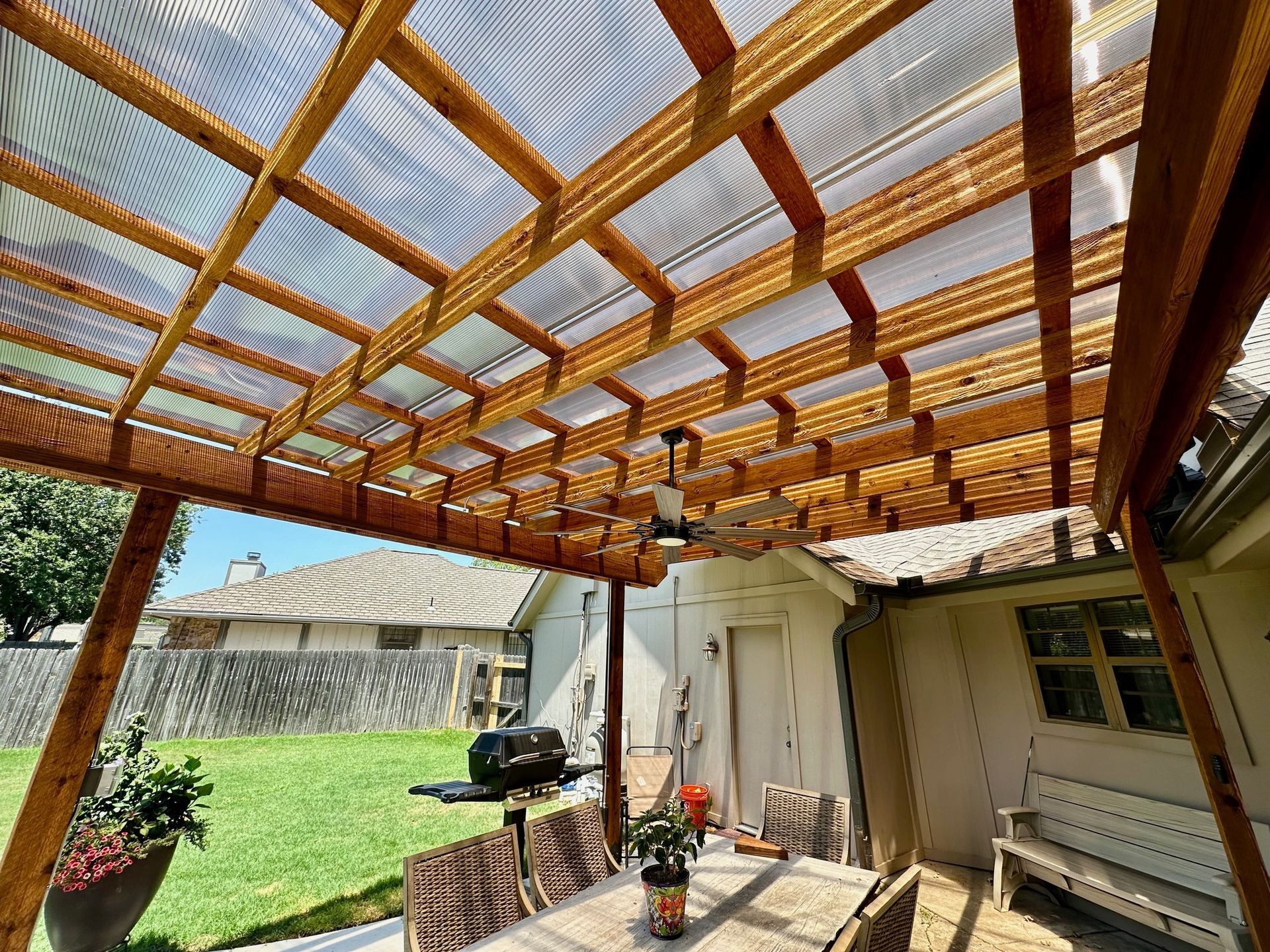 Wooden pergola with translucent roof over patio, outdoor setting.