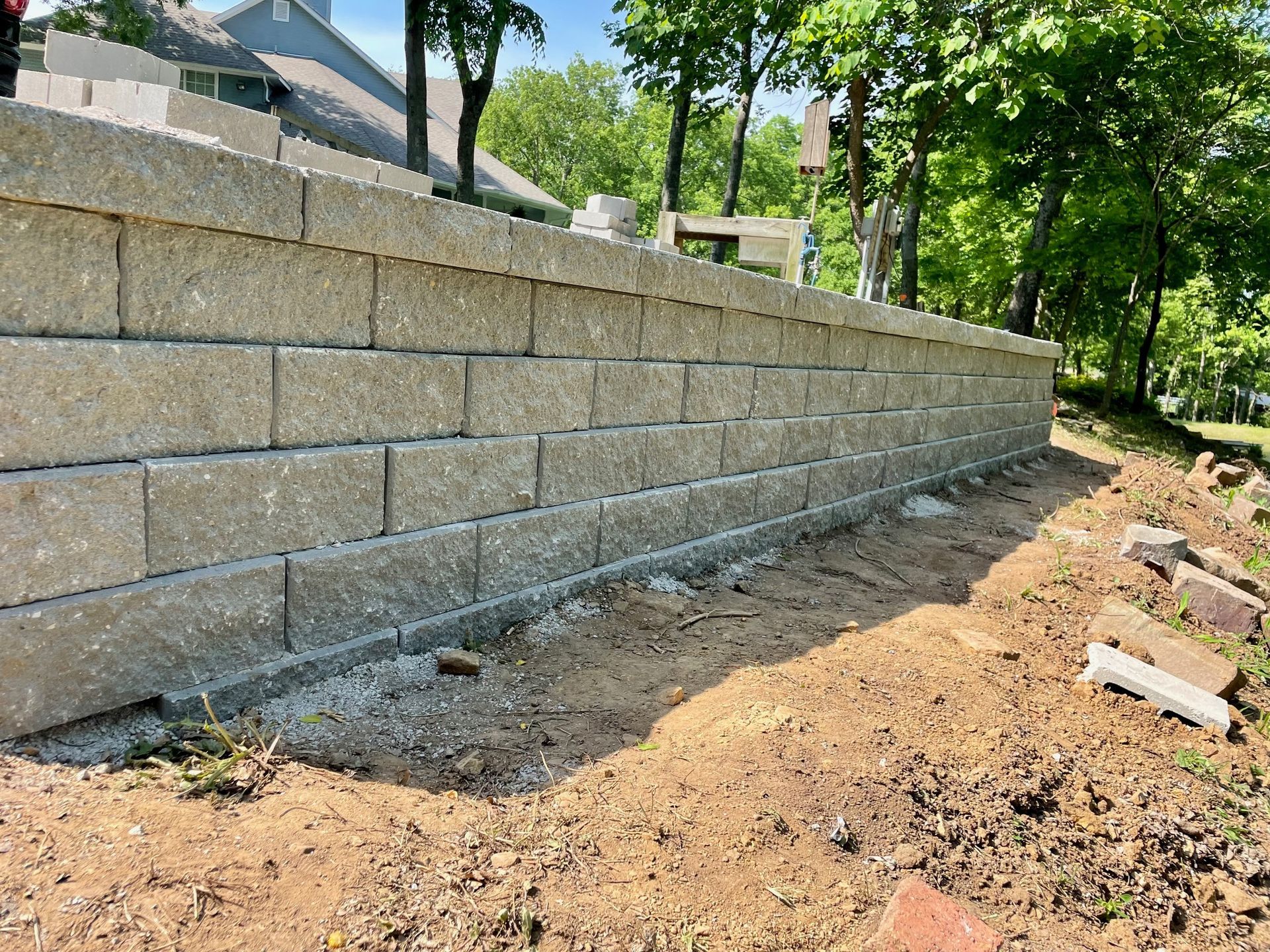 Concrete sidewalk with dark stain, next to brick pavers and dry grass.