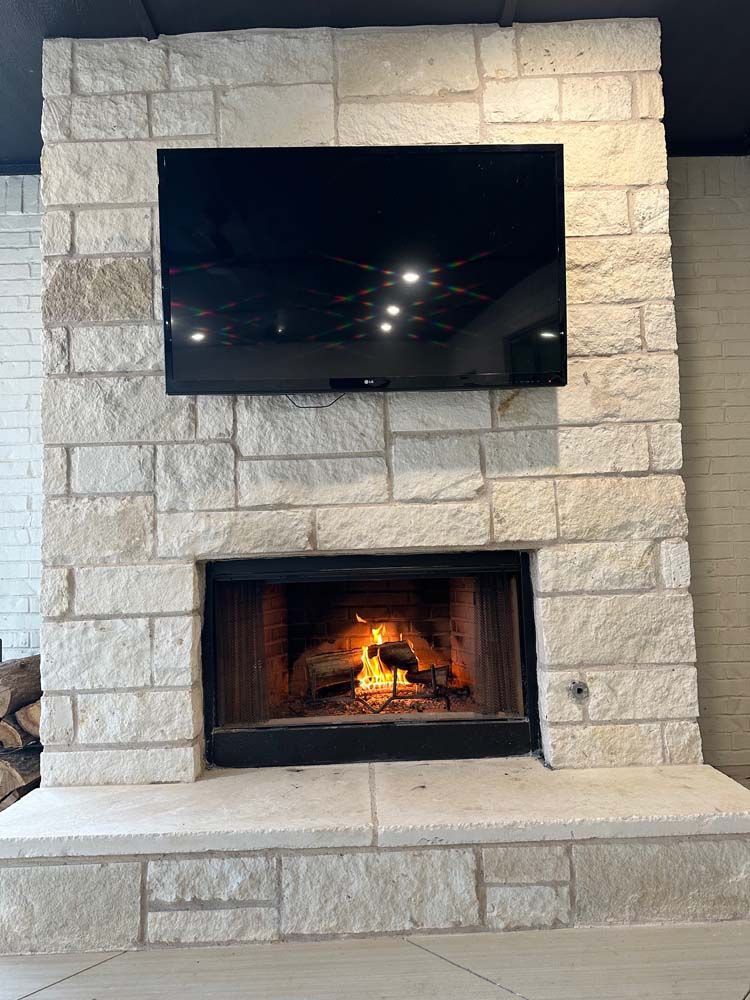 Fireplace with burning flames, mounted TV on stone facade, and hearth.